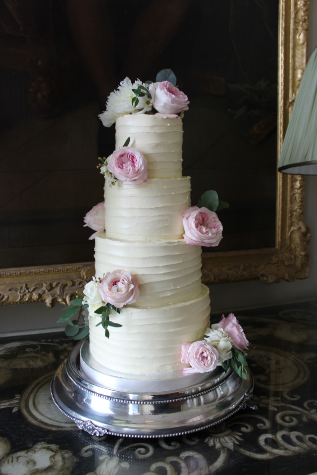 Four tier ribbed buttercream wedding cake decorated with fresh roses